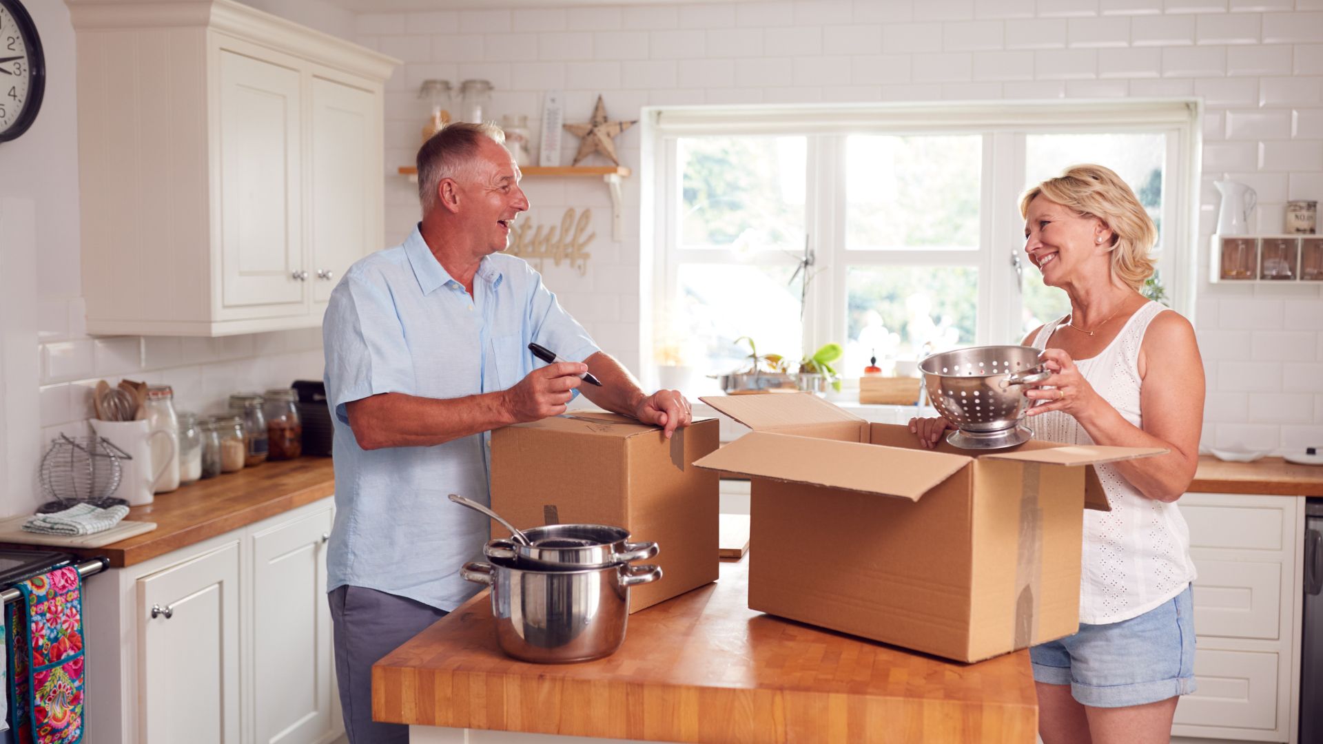 older man ands woman packing up boxes in their kitchen preparing to move